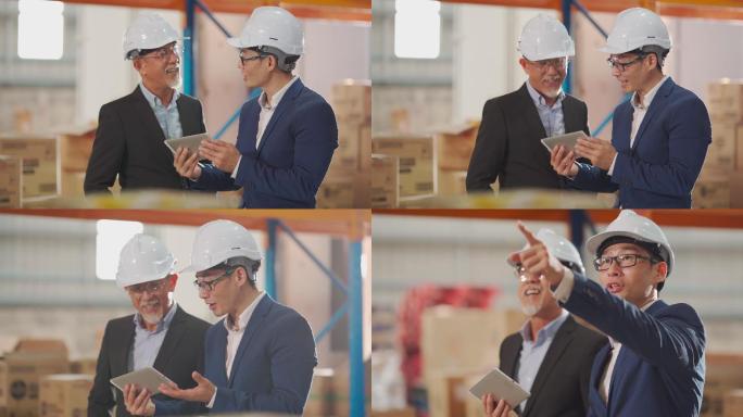 亚裔中国管理层在仓库与使用数字平板电脑的白色安全帽进行讨论