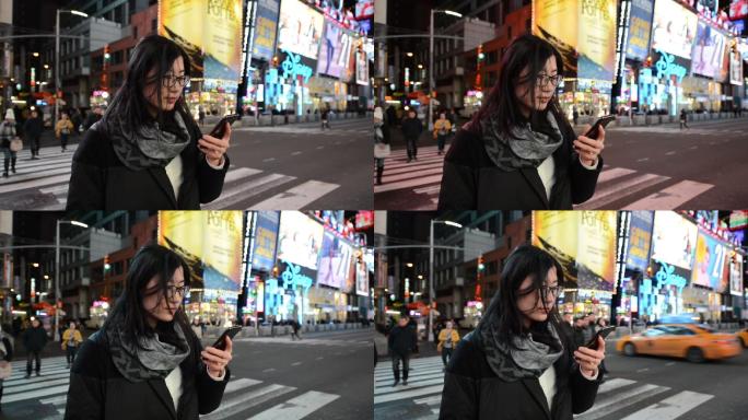 亚洲女性夜间在时代广场使用智能手机
