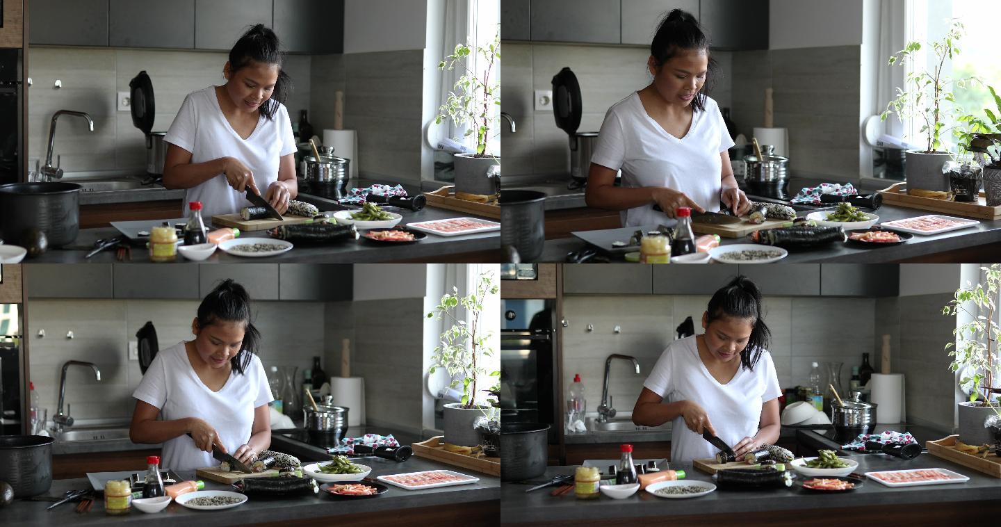 一名泰国妇女卷起寿司卷后，用锋利的刀将寿司卷切成小块