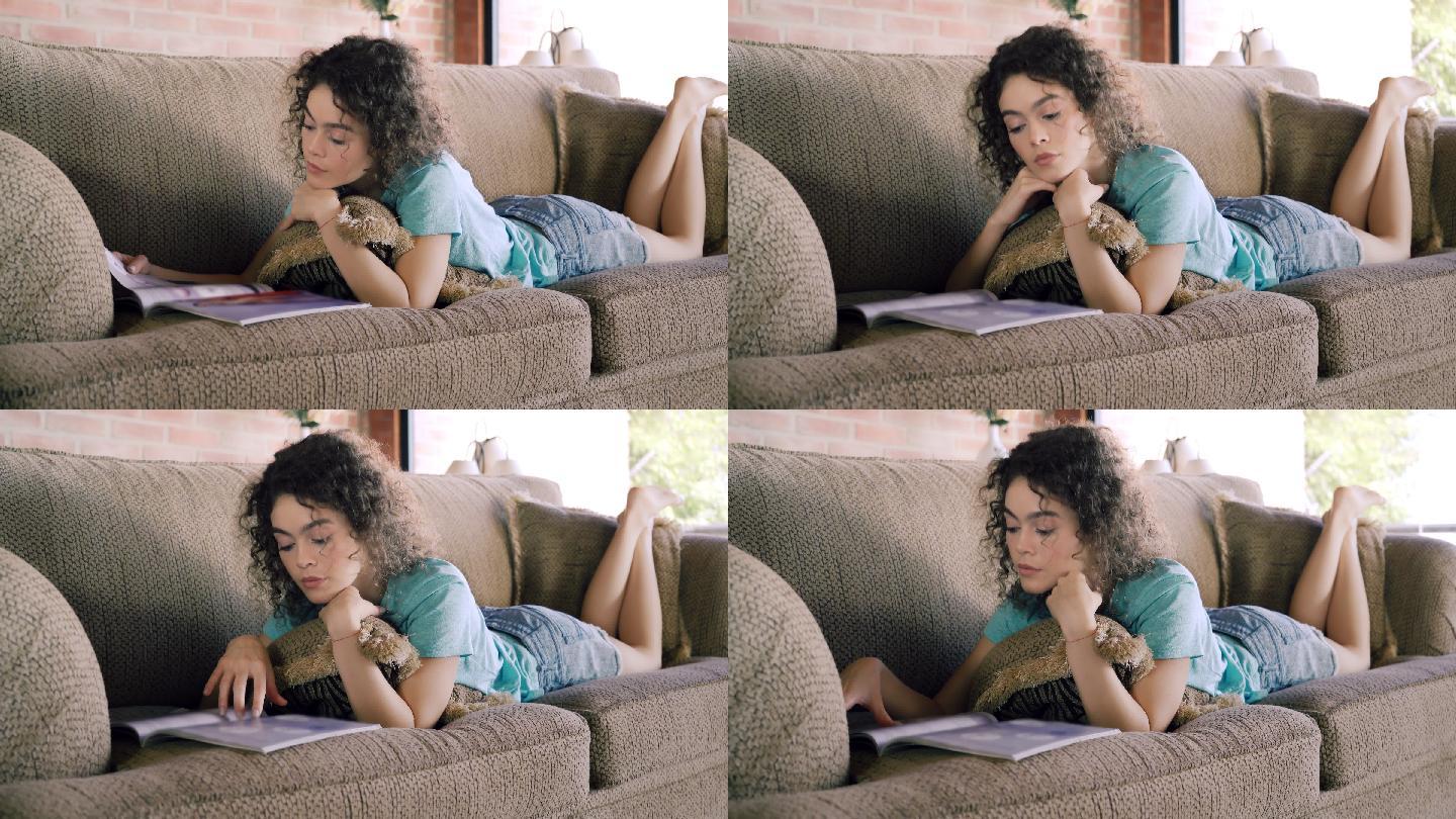 拉美裔卷发年轻女子在沙发上放松时看杂志