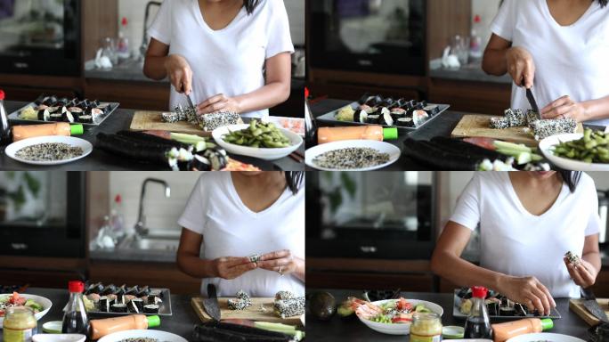 女寿司厨师将由内而外的寿司卷在砧板上切成一小块，然后放在盘子上