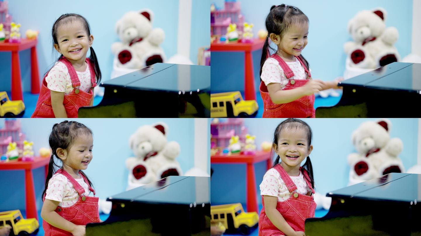美丽的亚洲小女孩在客厅里弹钢琴。可爱的学龄前儿童在学习乐器时很开心。女孩在鼓掌，很高兴。