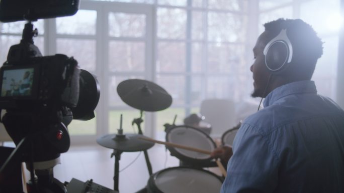 一名非洲裔男子在起居室练习电子鼓。