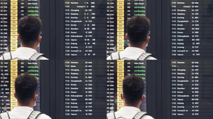 机场大厅航班动态显示屏查看信息的旅客背影
