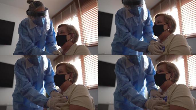 医生在家戴着口罩，将贴纸“接种疫苗”粘在一位老年妇女身上