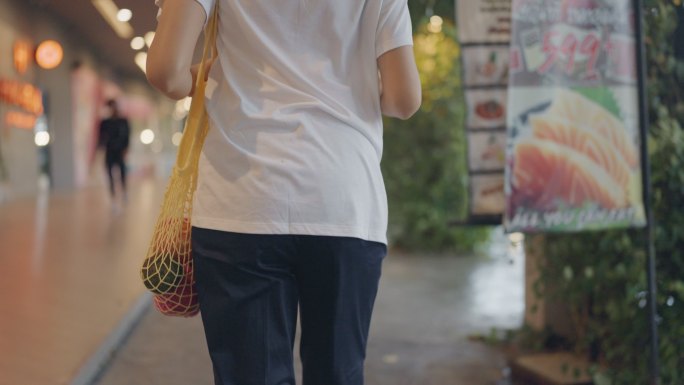 亚洲女性带着可重复使用的购物袋走进城市