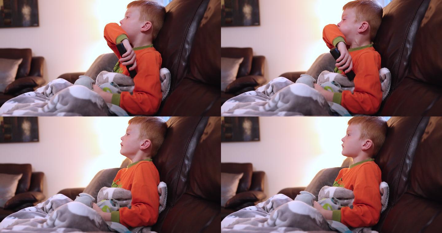 红头发的小男孩在家生病时坐在沙发上
