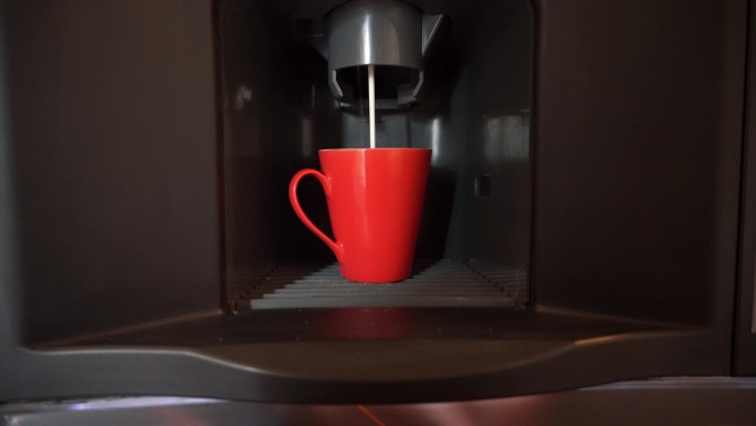 自动售货机中的瓷红色咖啡杯装满了咖啡