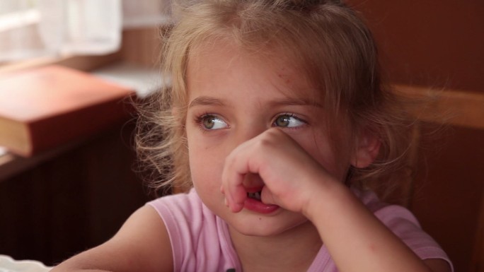 一个小女孩用手指扭动疼痛的牙齿的特写镜头