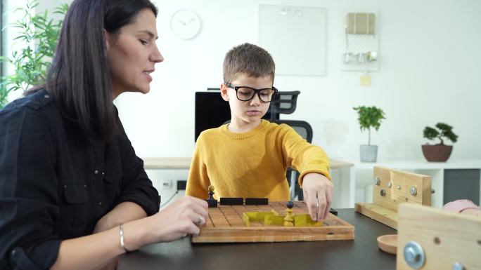 老师在托儿所和小男孩玩棋盘游戏