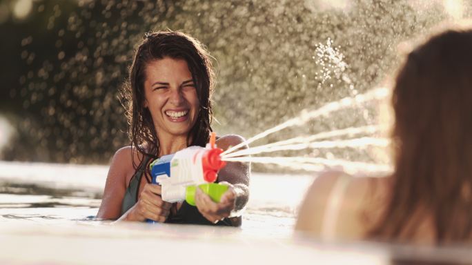 兴高采烈的年轻女子用水枪射水。