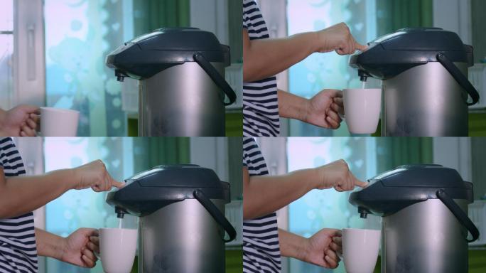 手上的特写镜头是按下电热锅上的按钮，将热水倒入陶瓷玻璃中。在厨房里，一位女士推着电热壶上的热水按钮喝