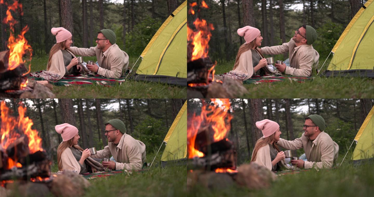 这对可爱的夫妇躺在营火旁喝茶。