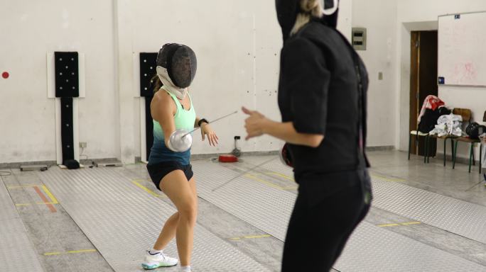 女子击剑运动员与教练一起训练攻击动作