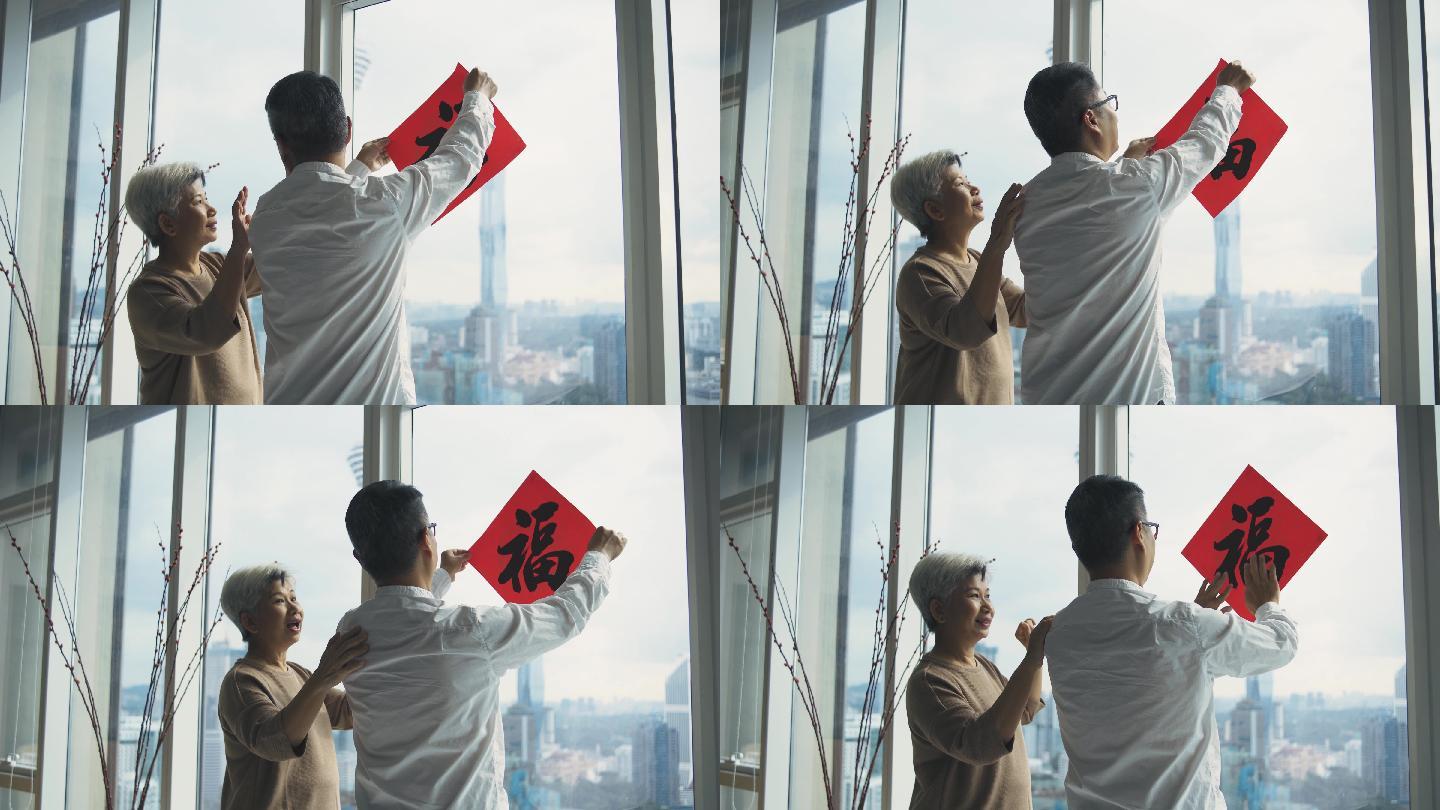 春节老人夫妇在窗户上用中国书法装饰客厅，为家庭团聚做准备