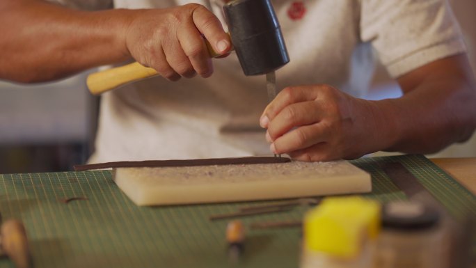 特写亚裔中国资深男子在工作室从事手工皮革表带皮革制作
