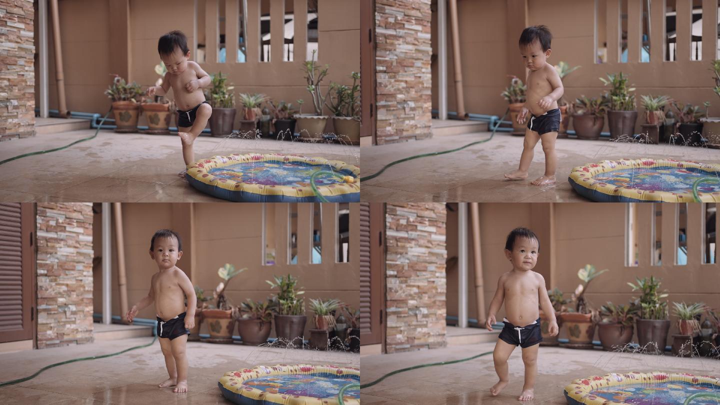 微笑的蹒跚学步的男孩在充气泳池中玩耍