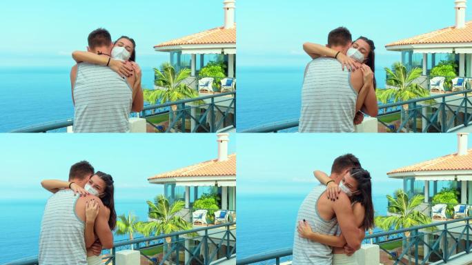 情侣们在可以看到海景的露台上，戴着防护面具拥抱在一起（FFP2型）。大流行时期的爱情