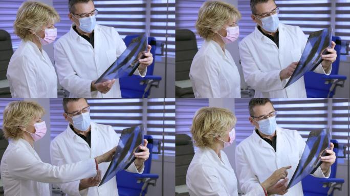 医生和他的女同事戴着防护面罩，检查X光片