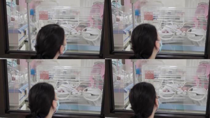 在医院里，母亲用爱和关怀看着保育箱中的婴儿。