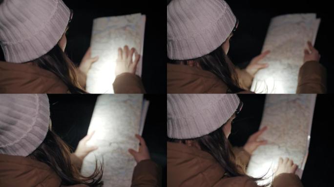 冬季旅行者在夜间看地图，一位年轻女性游客在冬季山脉中行走的特写镜头，肖像，旅行，探索，冒险，旅游，决