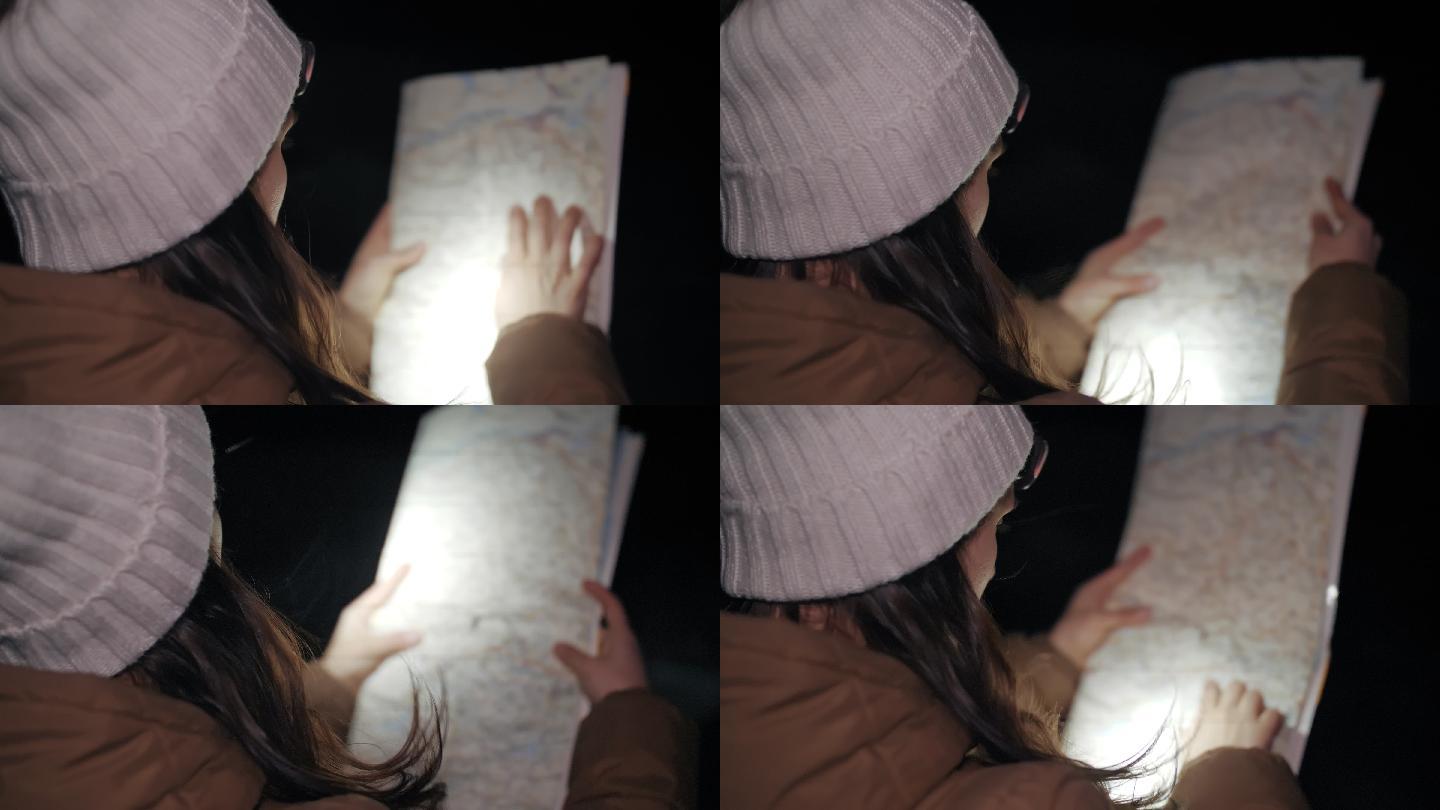 冬季旅行者在夜间看地图，一位年轻女性游客在冬季山脉中行走的特写镜头，肖像，旅行，探索，冒险，旅游，决