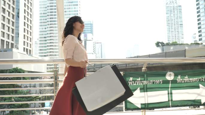 亚洲女性在贸易中心提着购物袋行走