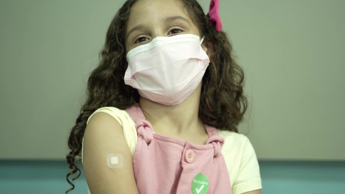 儿童用绷带和新冠疫苗贴片展示手臂