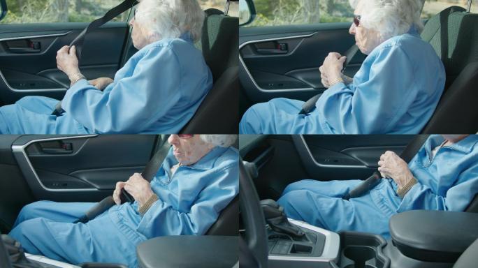 一位高加索老妇人在车内伸手拿着安全带扣