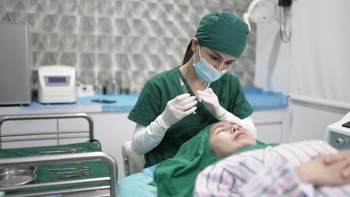 中国亚裔女医生在女性患者前额注射肉毒杆菌（肉毒杆菌）。