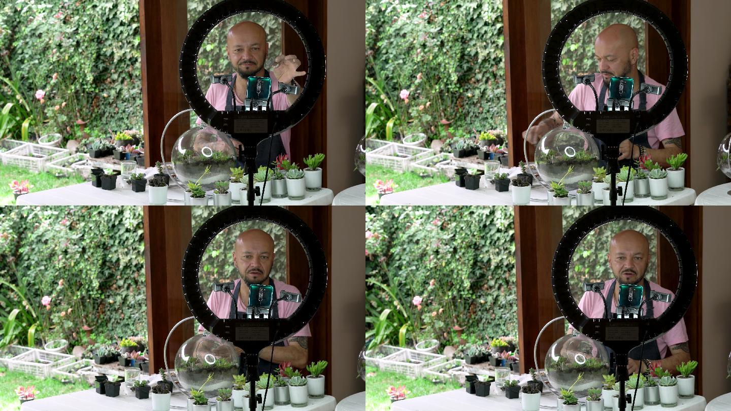 当他正在用他的多汁植物制作一个玻璃器皿来装饰时，影响者用他的光环和手机与他的追随者交谈