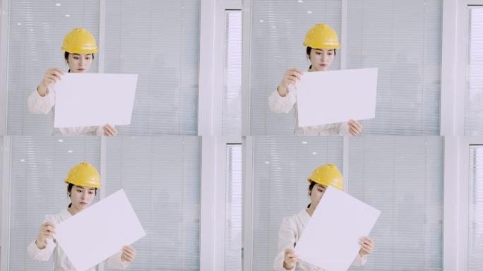 戴着黄色头盔的年轻漂亮的亚洲女工程师查看设计图纸