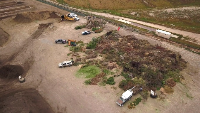 空中无人机视角下的有机覆盖堆肥设施，有成堆的树枝和有机材料用于回收