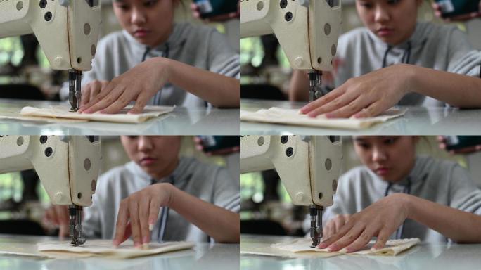 亚裔中国女时尚大学生在学院工作坊缝纫做衣服项目