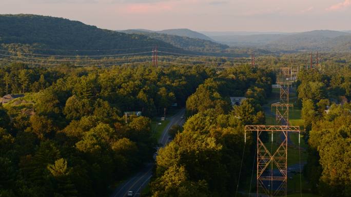 日落时分，宾夕法尼亚州一个小镇附近山区的高压电线。具有复杂向后平移摄影机运动的空中镜头。