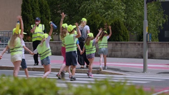 小学生和教师在红绿灯旁与两名过路警卫交叉路口