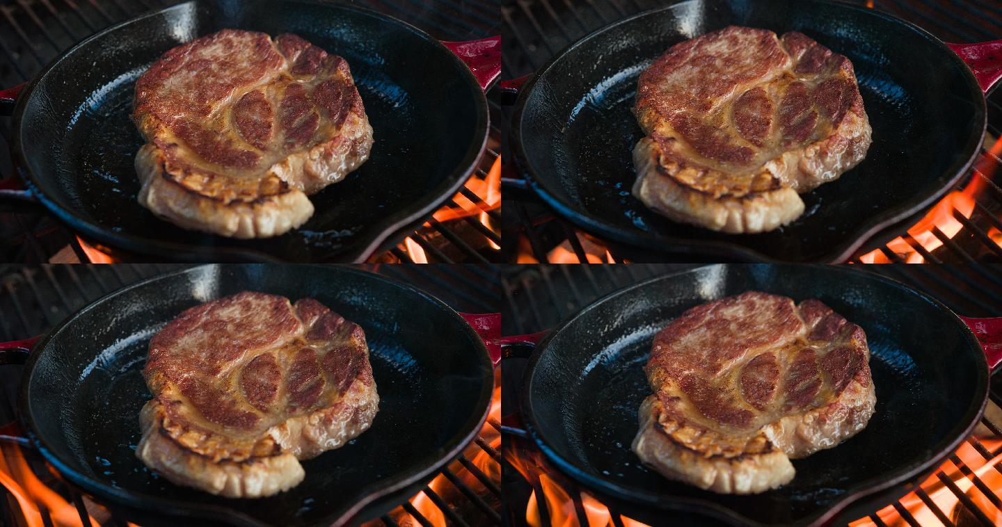 用铸铁煎锅在明火烤架上烹饪美味的牛排