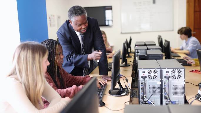 在高中计算机实验室帮助学生使用计算机的老师