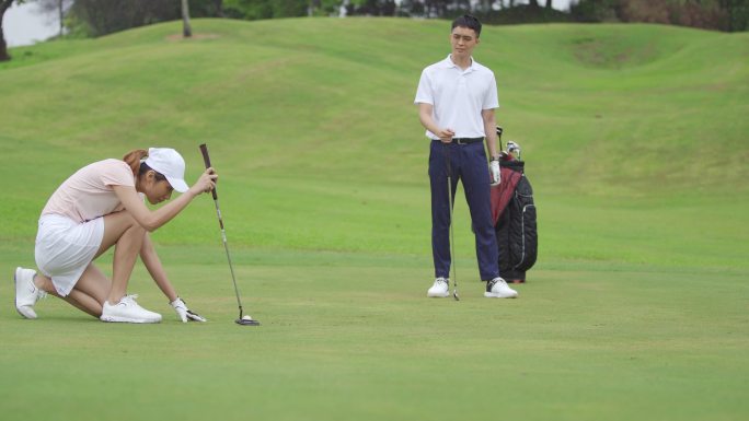 成熟的中国亚裔女子高尔夫球手在朋友在高尔夫球场观赛时，将推杆摆成一排