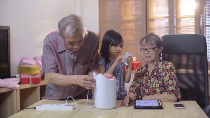 一对老人和一个女孩在家一起使用家电智能家居技术