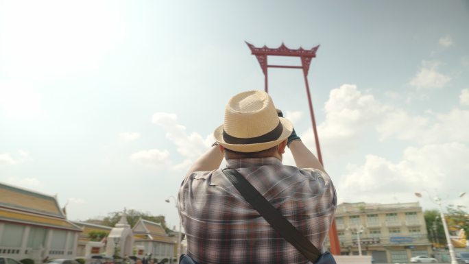 曼谷轮椅旅游地标概念。亚洲男性游客在曼谷的巨型摇摆地标拍照留念