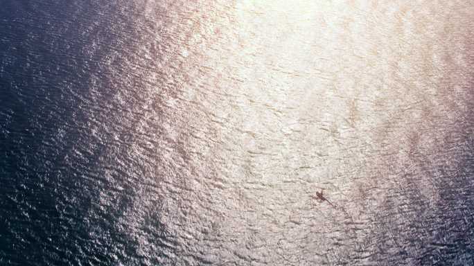 空中直升机在阳光下飞越海洋