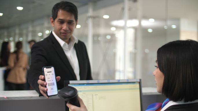 机场候机室商人手持手机扫描电子机票照片