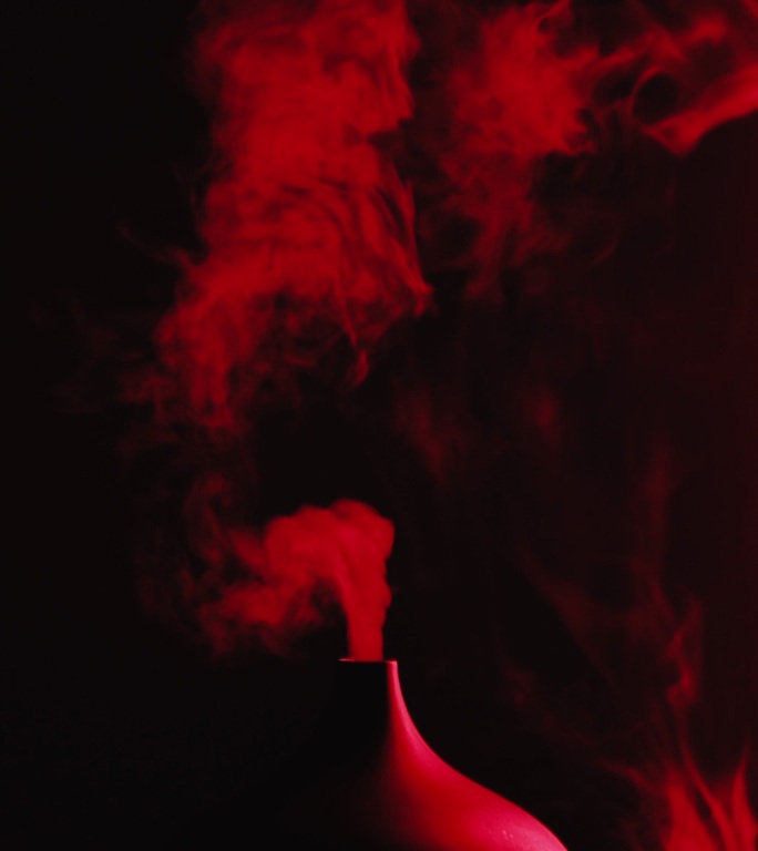 精油疗法，桌上的芳香油扩散灯，芳香疗法，来自芳香油扩散器的彩色蒸汽，来自芳香油扩散器的蒸汽，红色烟雾