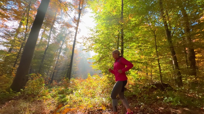 阳光明媚的秋日，在森林里奔跑的女人