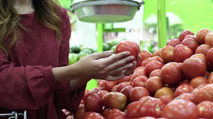 一位在杂货店里的拉丁女人根据自己的喜好挑选西红柿，然后把它们放进购物车