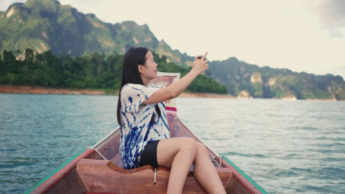 在泰国高索国家公园乘船旅行时，一名亚洲女性用智能手机拍照