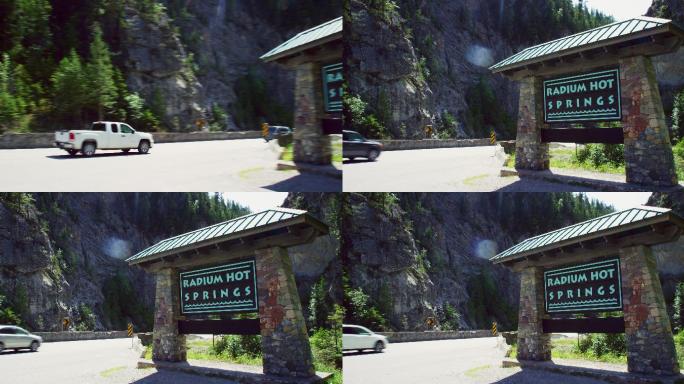 阳光明媚的一天，加拿大不列颠哥伦比亚省的加拿大落基山脉，汽车和其他车辆行驶在“镭温泉”标志旁的全景照