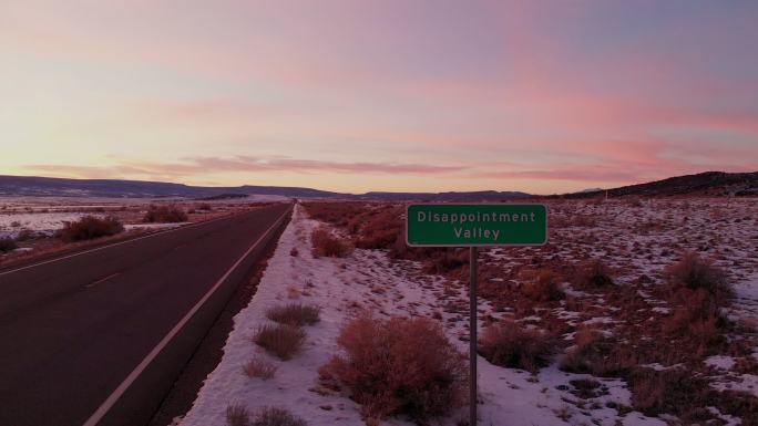 无人驾驶飞机拍摄了科罗拉多州一个真实的路标，上面写着失望谷，一个充满绝望和沮丧的地方，美丽的日落