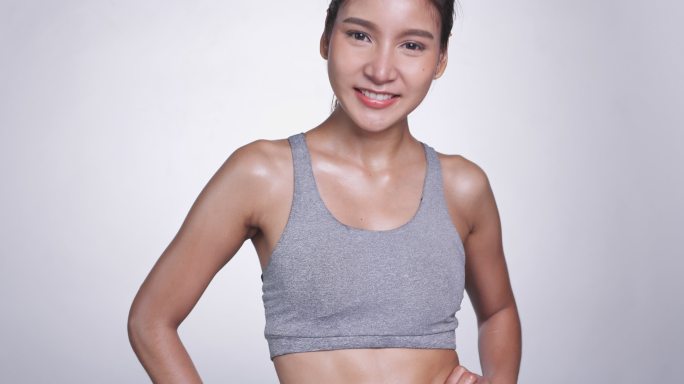 白色背景的年轻亚洲女性看着自己的腹部和腰部进行锻炼和控制饮食。